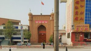 疏勒縣納丘克路上的清真寺外有警察巡邏，寺頂豎立著中國國旗