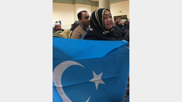 一名居住在英國的維吾爾族穆斯林手持東突厥斯坦旗幟，對流亡維吾爾人而言這面旗象徵著失去的家園