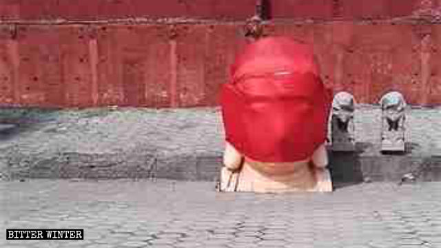 一個被拆毀的佛像頭被紅布包裹