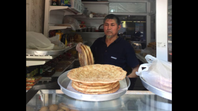 這位來自喀什的師傅正自豪地展示剛從烤爐中新鮮出爐的nan餅。