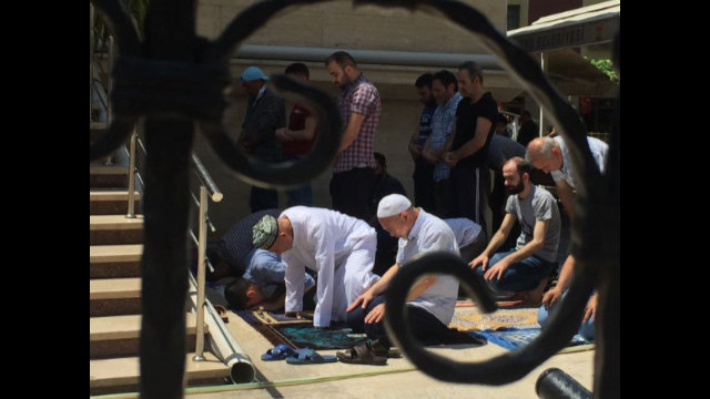 主麻日，在伊斯坦布爾郊區宰廷布爾努禱告中的維吾爾人。請注意左邊前排的維吾爾男子頭上戴著富有民族特色的刺繡「多巴」（維吾爾人戴的花帽）或無邊便帽。在土耳其，他們可以自由地作禱告，但他們在中國的同胞卻被禁止到清真寺做禮拜，許多人就是因為做禮拜遭到了關押。