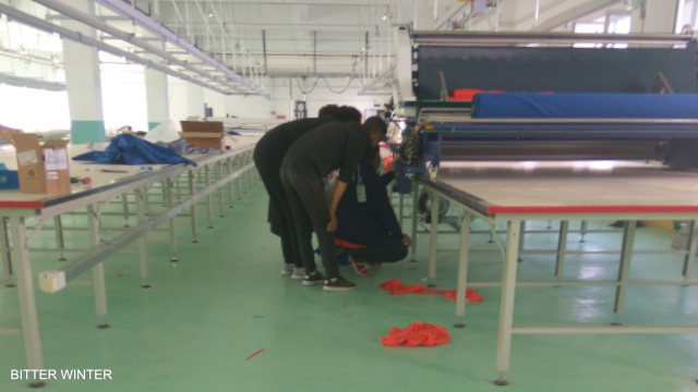 在新疆伊寧市教育轉化營內人們被強制勞役、從事「合適工作」的其中一個廠房內，工人正在調試機器。