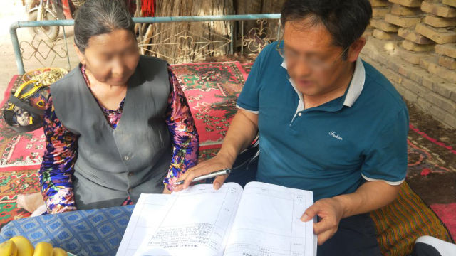 新疆某地政府人員正在讓老婦人看資料（網絡圖片非当事人）