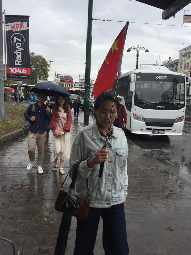 一名导游带着游客穿梭在古老的集市之间，中国国旗高高地飘扬在伊斯坦布尔街头