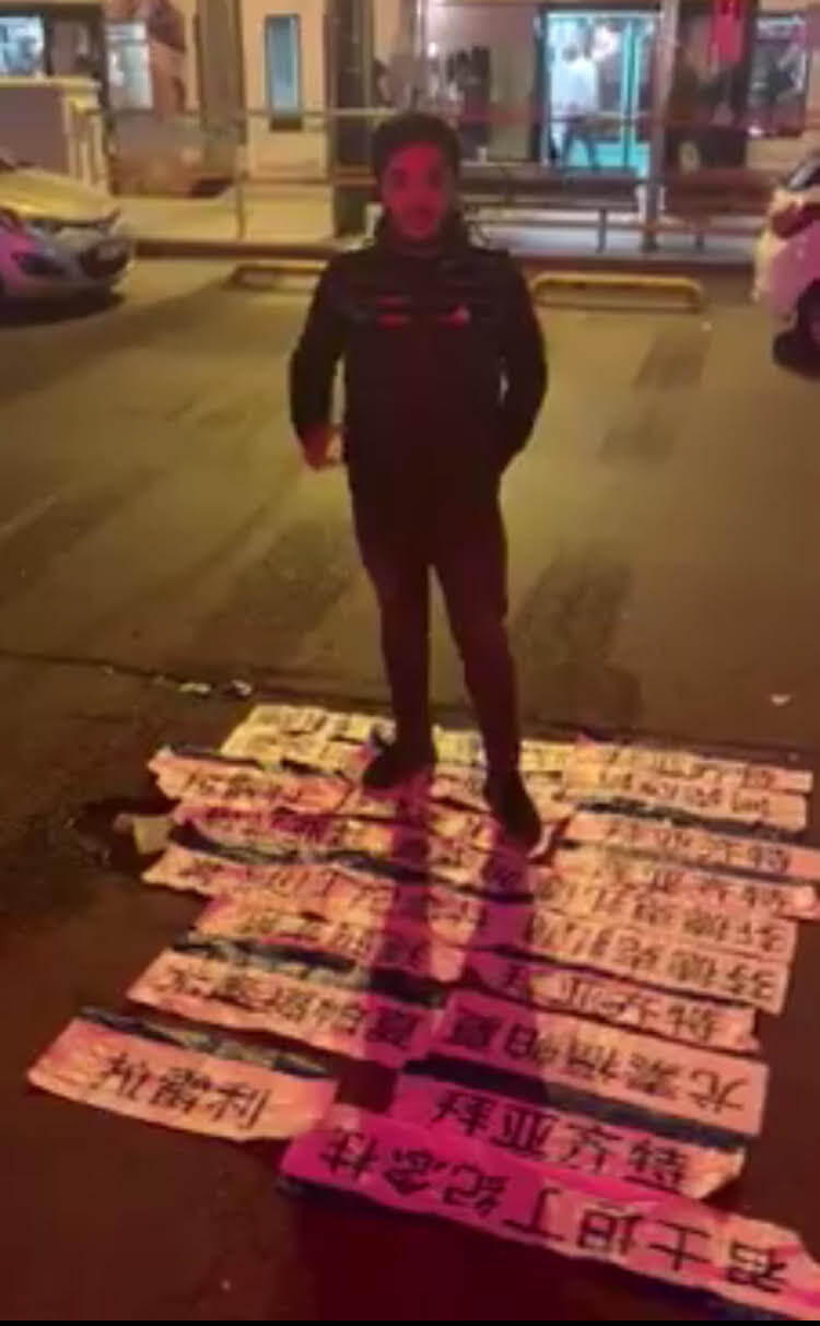 一名维吾尔青年踩在中文电车站名标志上，那些是他和支持他们的土耳其民众一夜之间撕下的