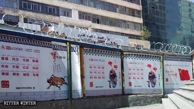 一佈滿了鐵絲網的圍牆上懸掛著習近平「中國夢」的宣傳海報